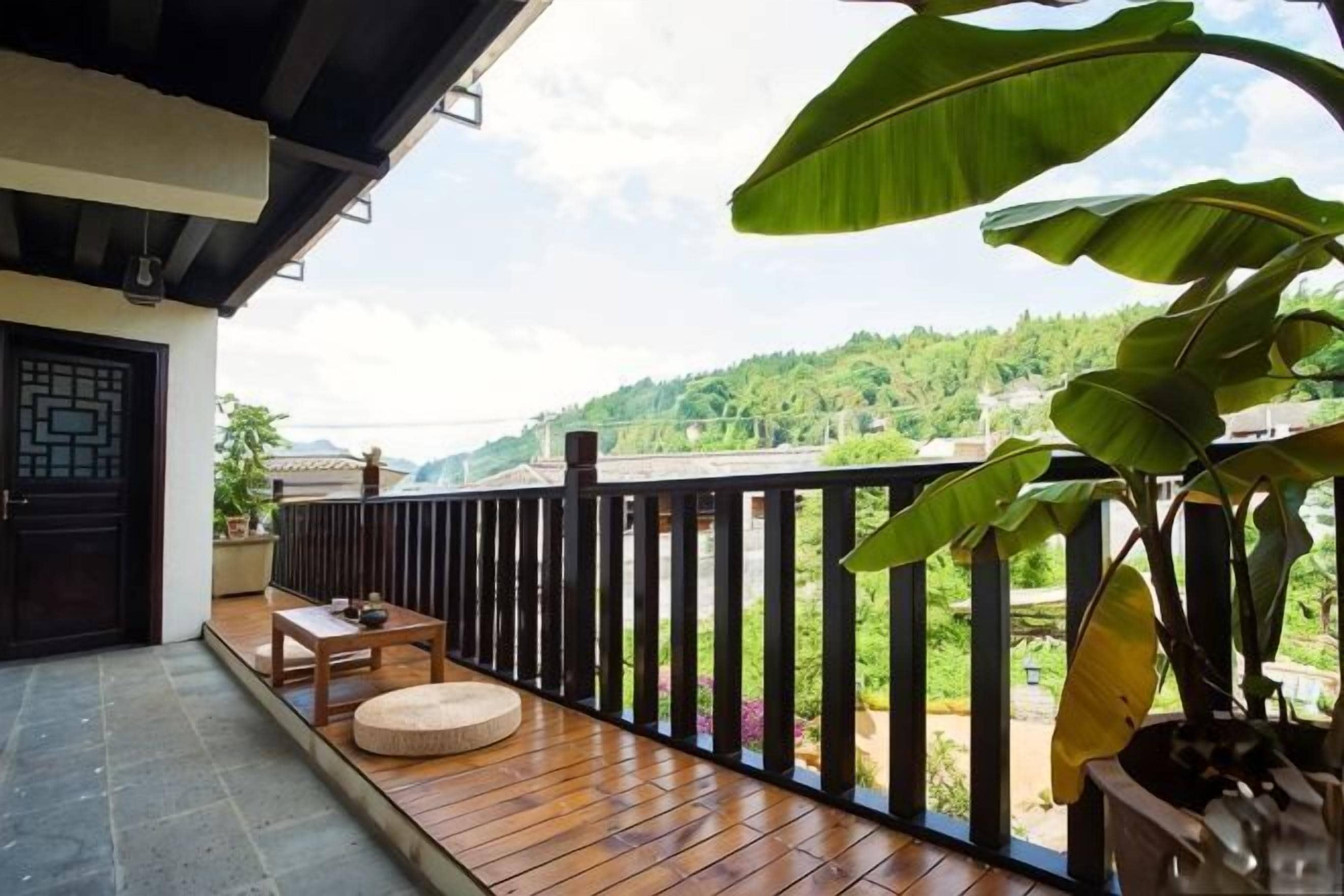 Un balcón con piso de madera, un espacio de estar circular y vistas a un paisaje verde.