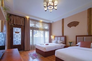 A hotel room with two beds, a television, a wooden desk, and a decorative wall piece.