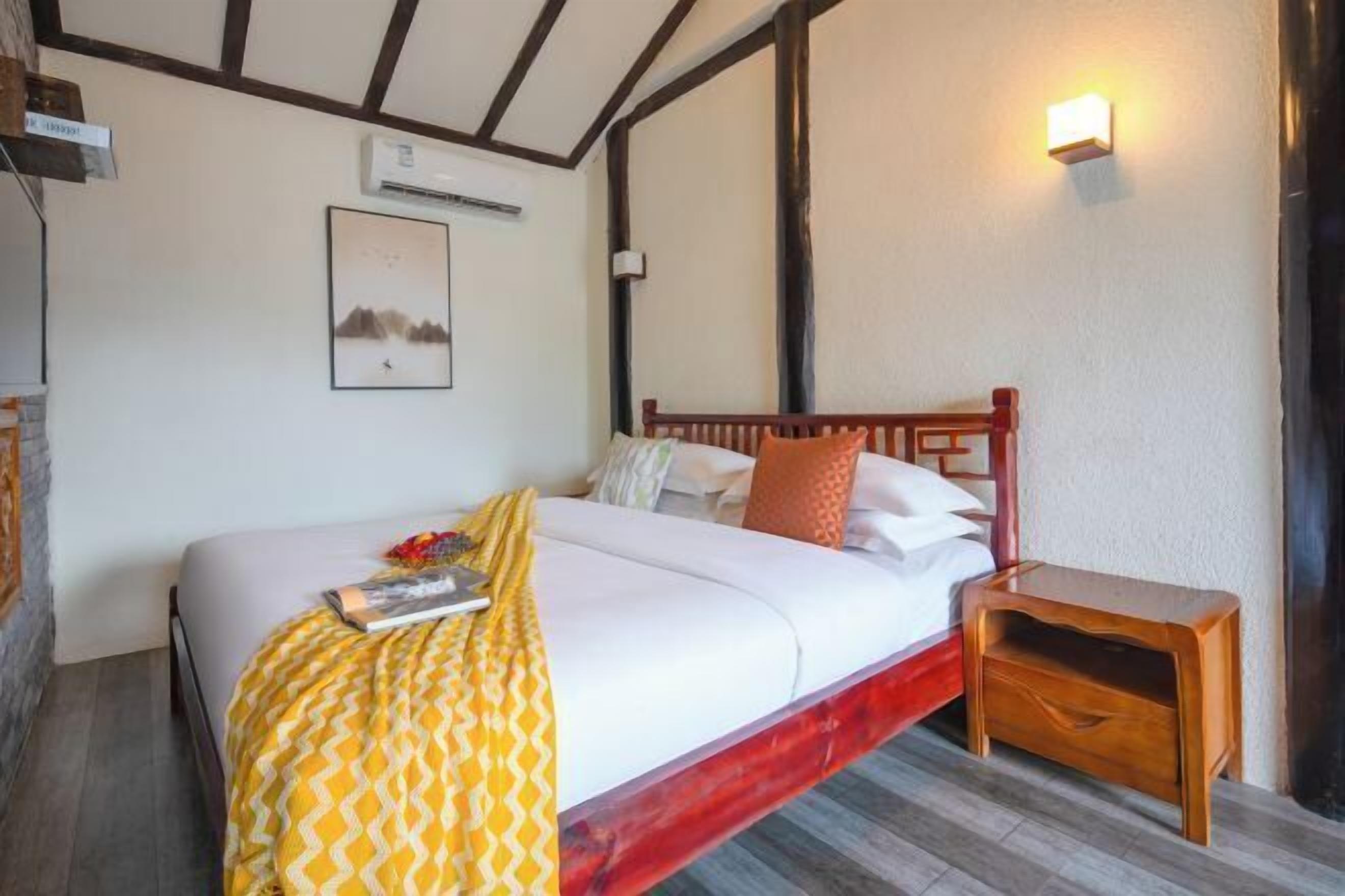 Ein Schlafzimmer mit einem Bett, einem Nachttisch, einer Wandleuchte und einem Gemälde.