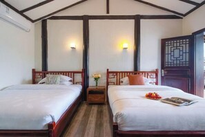 A hotel room with two wooden beds, a nightstand with a vase of flowers, and a traditional door with a geometric pattern. - Colorful·Muyun inn (Tengchong)