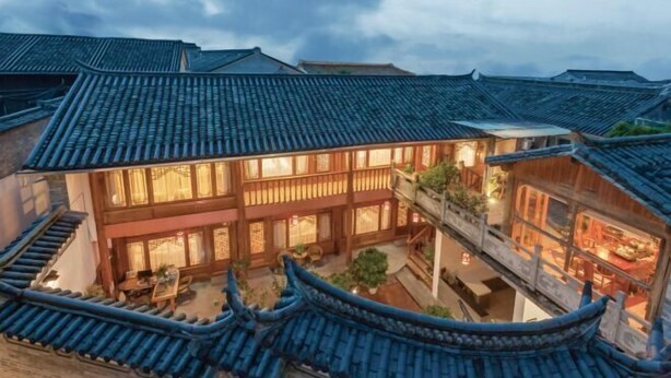 A traditional courtyard with multiple buildings, wooden balconies, and a central open space.