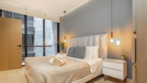 A modern bedroom with a large bed, bedside tables, and a view through a window. - Musa del Carmen By BoutiqueApartments MX (Playa del Carmen)