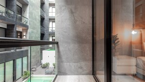 A modern hotel interior with a balcony overlooking a pool and a courtyard. - Musa del Carmen By BoutiqueApartments MX (Playa del Carmen)