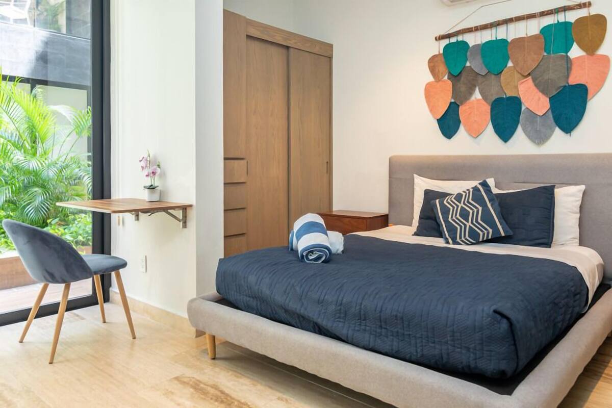 Ein Schlafzimmer mit einem Bett, einem Schreibtisch, einem Sessel und einem Wandbild.