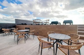 An outdoor seating area with wicker chairs and tables, a wooden wall, and a view of the sky. - Musa del Carmen By BoutiqueApartments MX (Playa del Carmen)