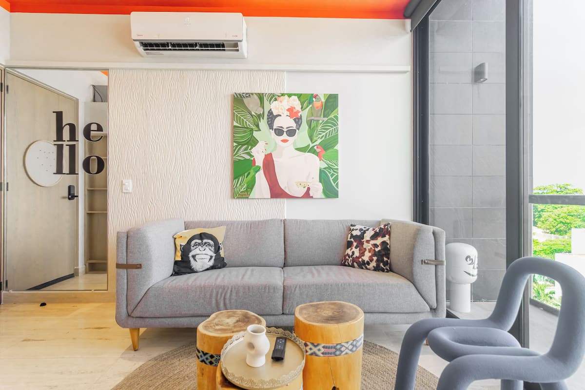 Ein modernes Wohnzimmer mit einem grauen Sofa, Holzschemeln und einem Bild an der Wand.