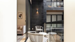 A modern interior with a sofa, wicker chairs, and a glass partition. - Musa del Carmen By BoutiqueApartments MX (Playa del Carmen)