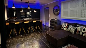 A modern kitchen with a bar area, a seating area with a sofa and chairs, and a decorative wall piece. - Le Splendide !!!!! (Lévignacq)