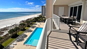 Uma varanda com piscina, com vista para a praia e oceano.