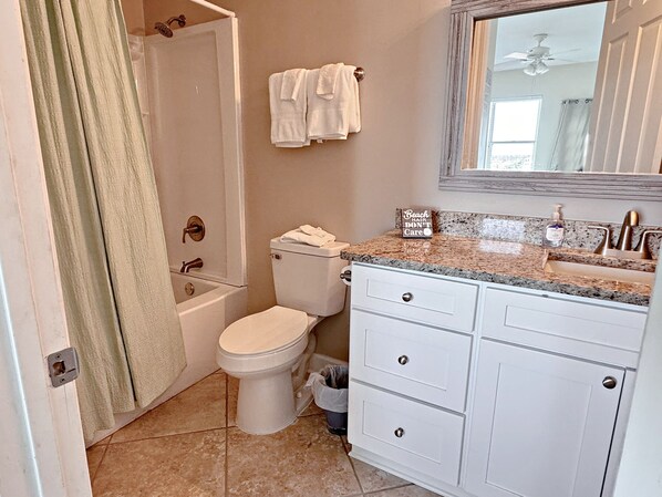 A bathroom with a bathtub, toilet, and vanity with drawers.