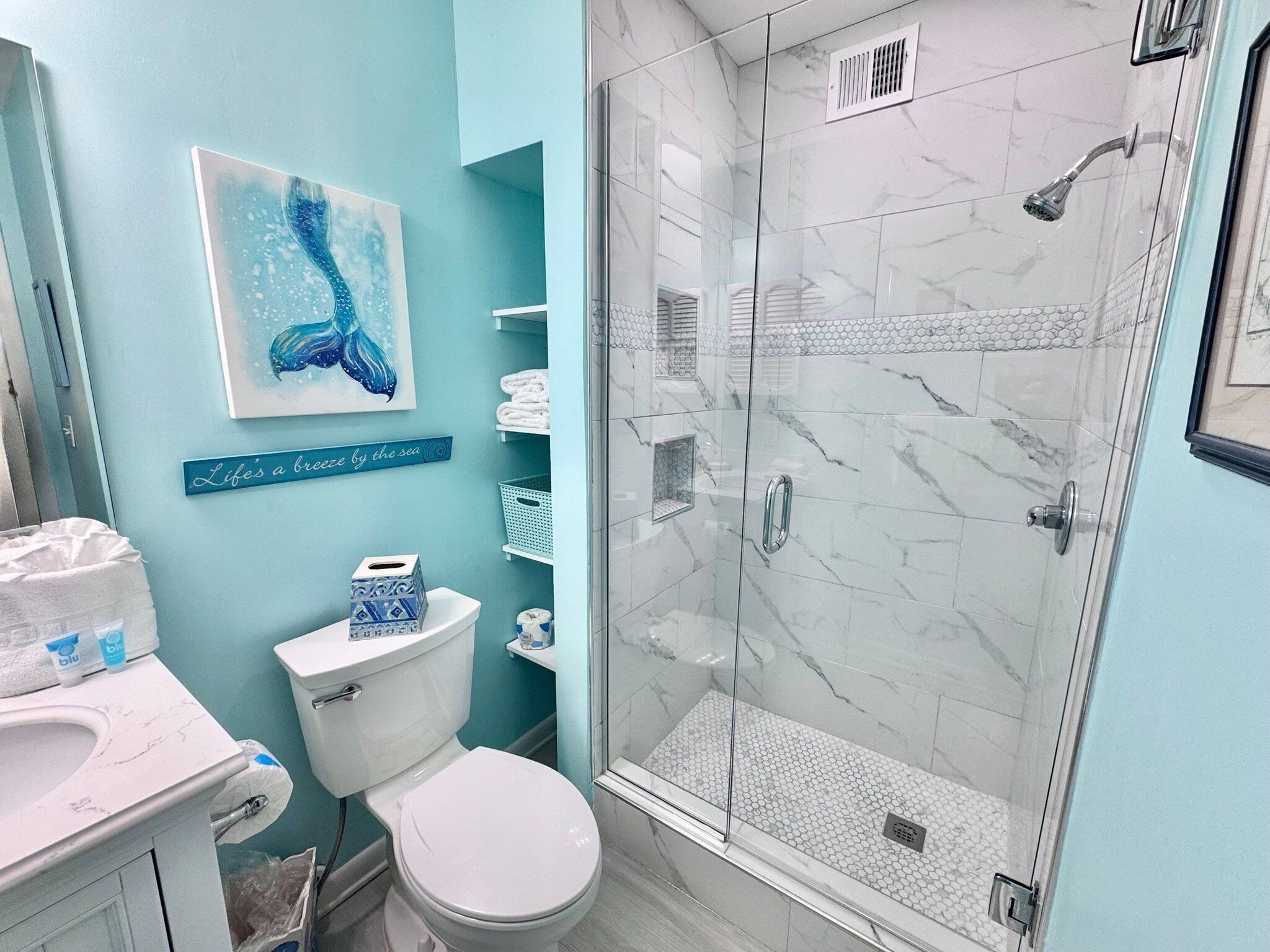 A bathroom with a toilet, sink, and glass-enclosed shower.