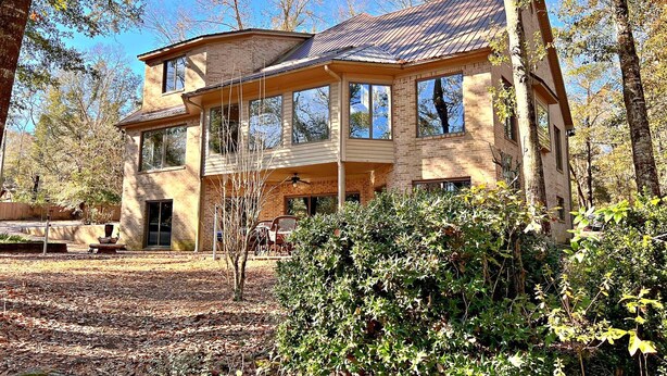 A two-story house with a large porch, surrounded by trees and a leaf-covered ground. - Daphne River Villa (Daphne)