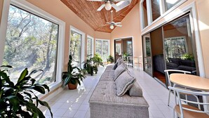 A sunlit room with a ceiling fan, large windows, and a sofa with cushions. - Daphne River Villa (Daphne)