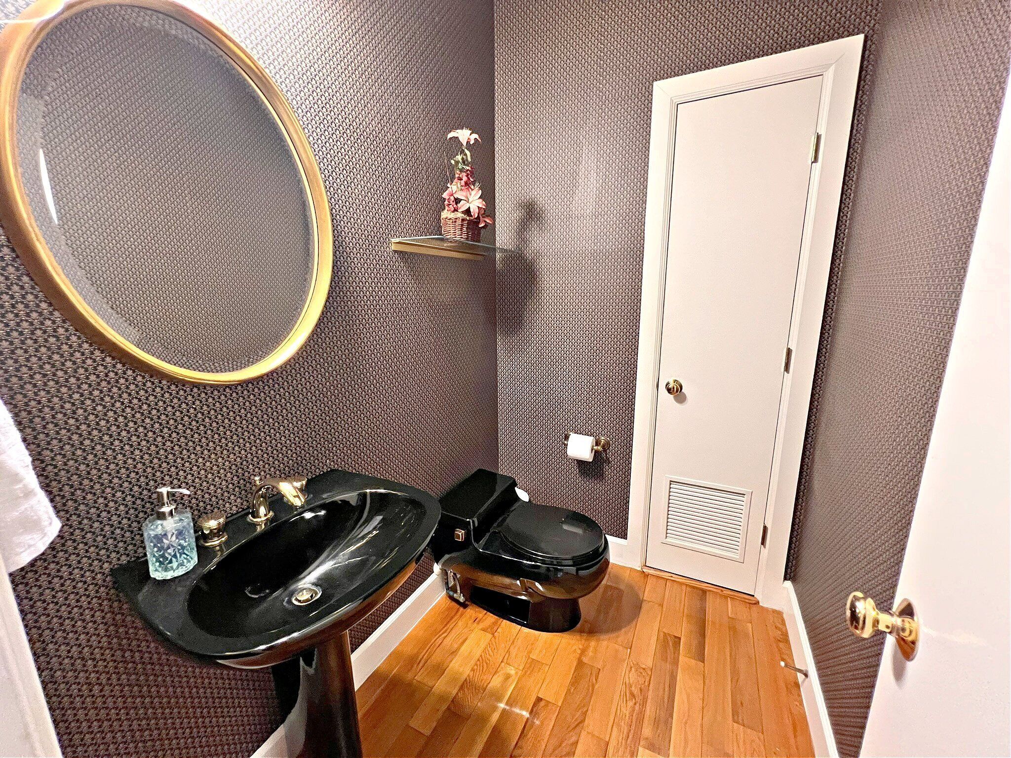 A bathroom with a black sink, a toilet, a mirror, and a towel rack.