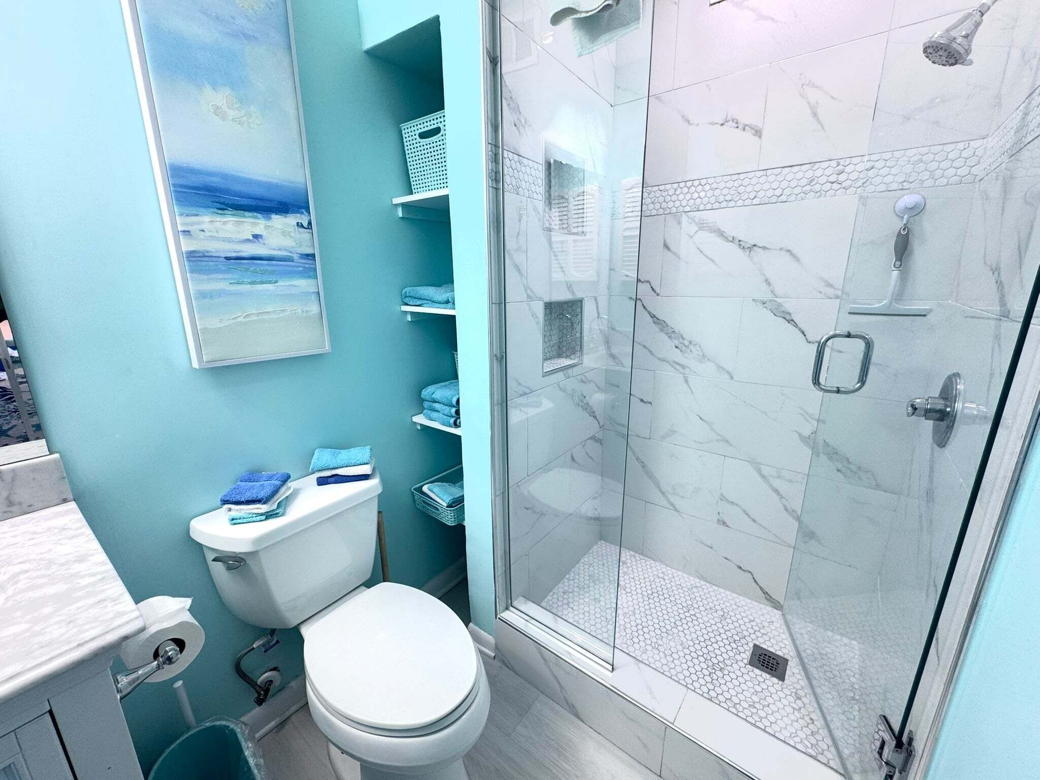 Un bagno con un WC, una doccia e uno scaffale a parete con asciugamani.