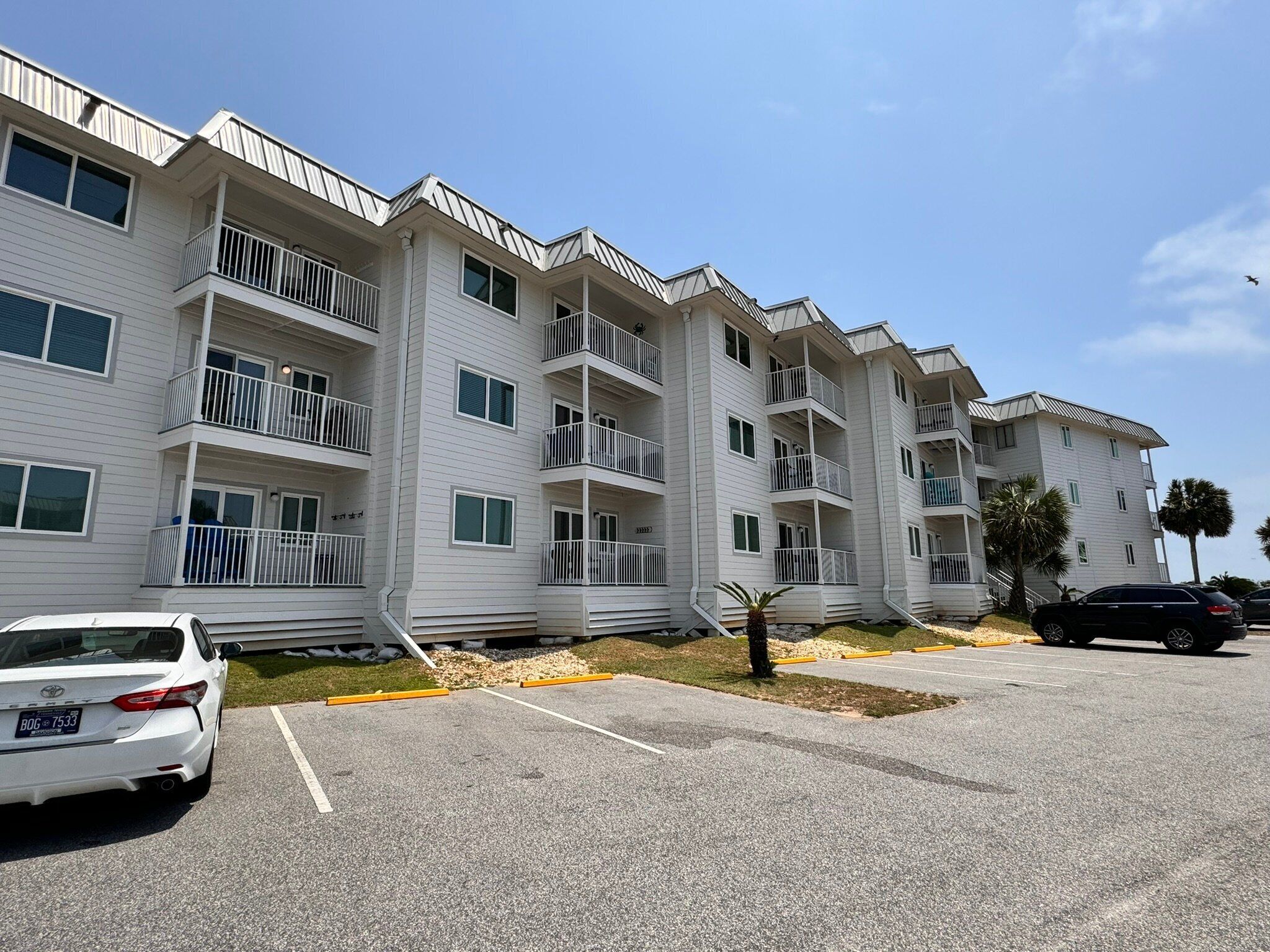 Un immeuble d’appartements à plusieurs étages, doté de balcons, d’un parking et surplombant un ciel dégagé.
