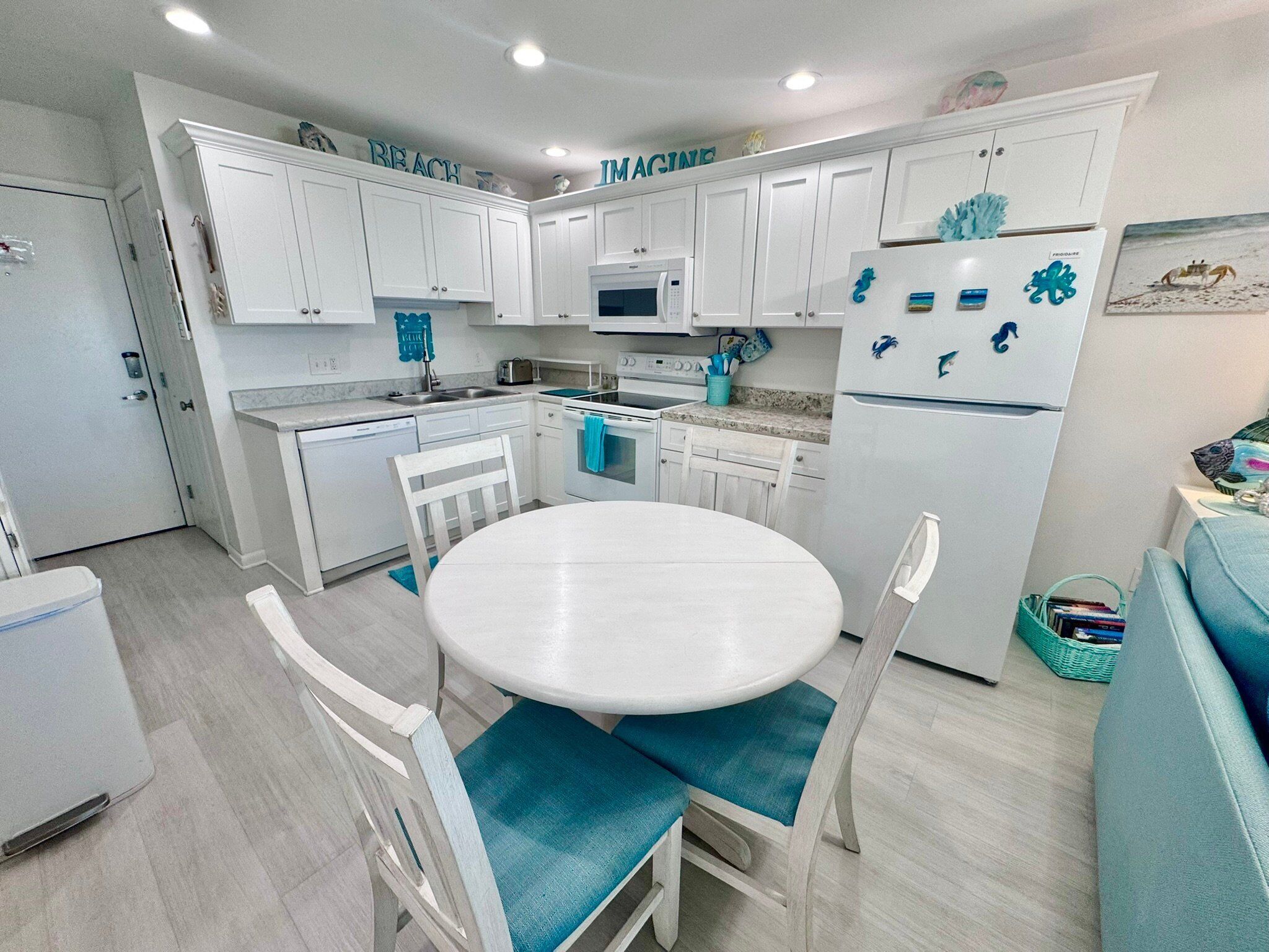A compact kitchen with white cabinets, a microwave, a refrigerator, and a dining table with chairs.