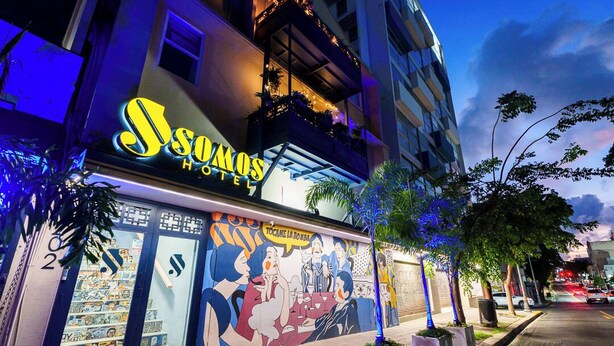 A hotel with a colorful mural on the facade, a sign reading "Hotel Sodomos", and a balcony with plants. - Queen Bee @ Somos Hotel (SanJuan)