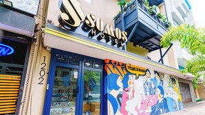 A hotel with a colorful mural on the facade, a visible entrance, and a balcony with plants. - Queen Bee @ Somos Hotel (SanJuan)