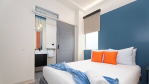 A modern hotel room with a large bed, a bathroom with a mirror, and a window. - Queen Bee @ Somos Hotel (SanJuan)
