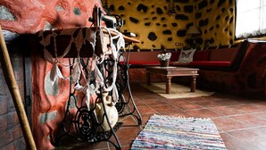 A rustic room with a stone wall, a wooden table, a patterned rug, and a sofa.