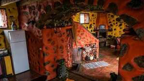 A rustic kitchen with a stone wall, a staircase, and a sewing machine on a table.