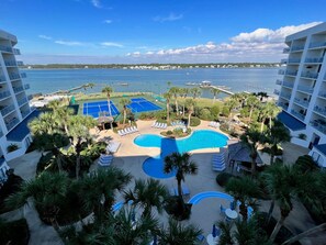 Un resort con piscina, canchas de tenis y vista al mar.
