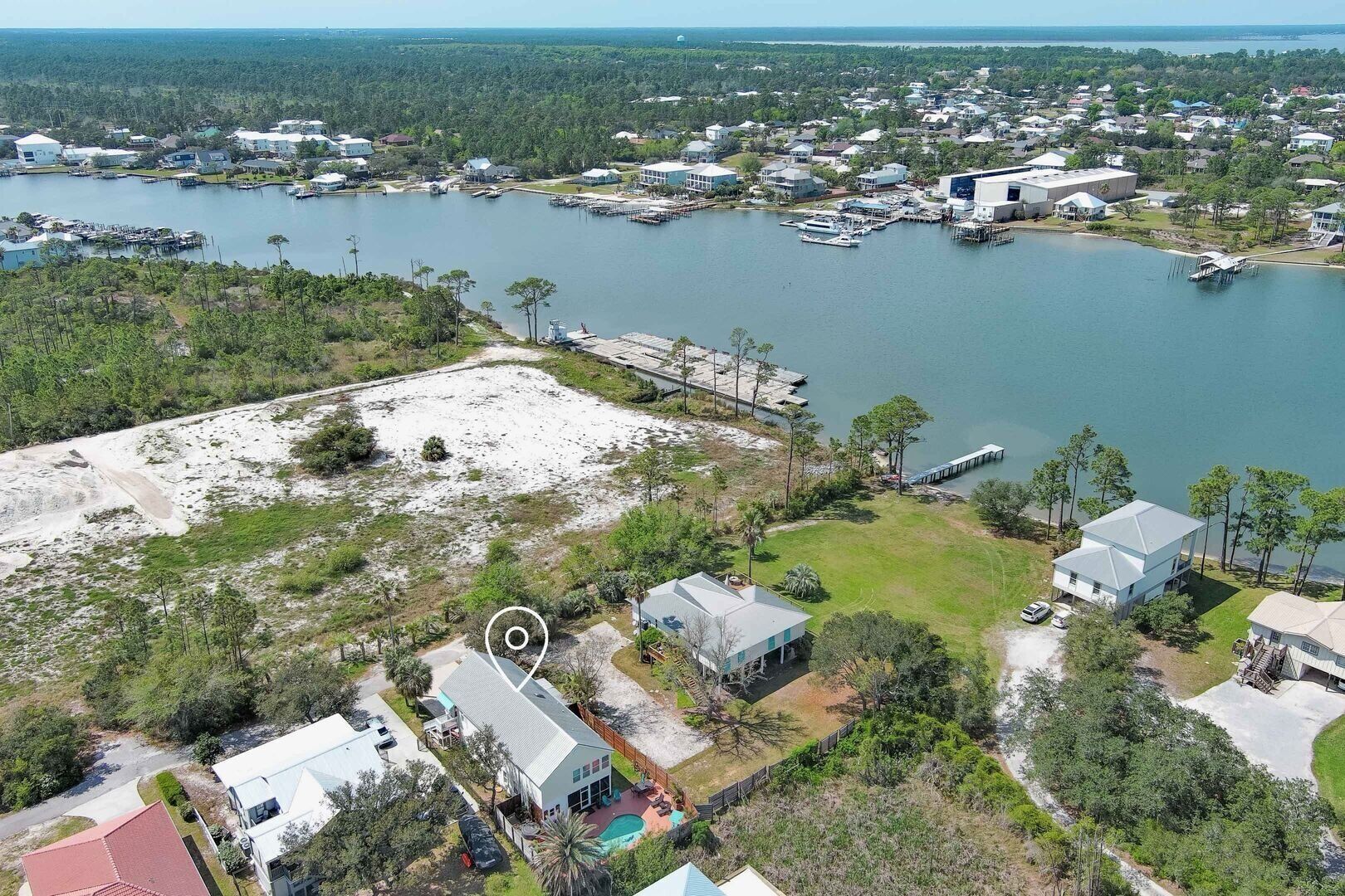 An aerial view of a coastal residential area with houses, docks, and a large body of water.