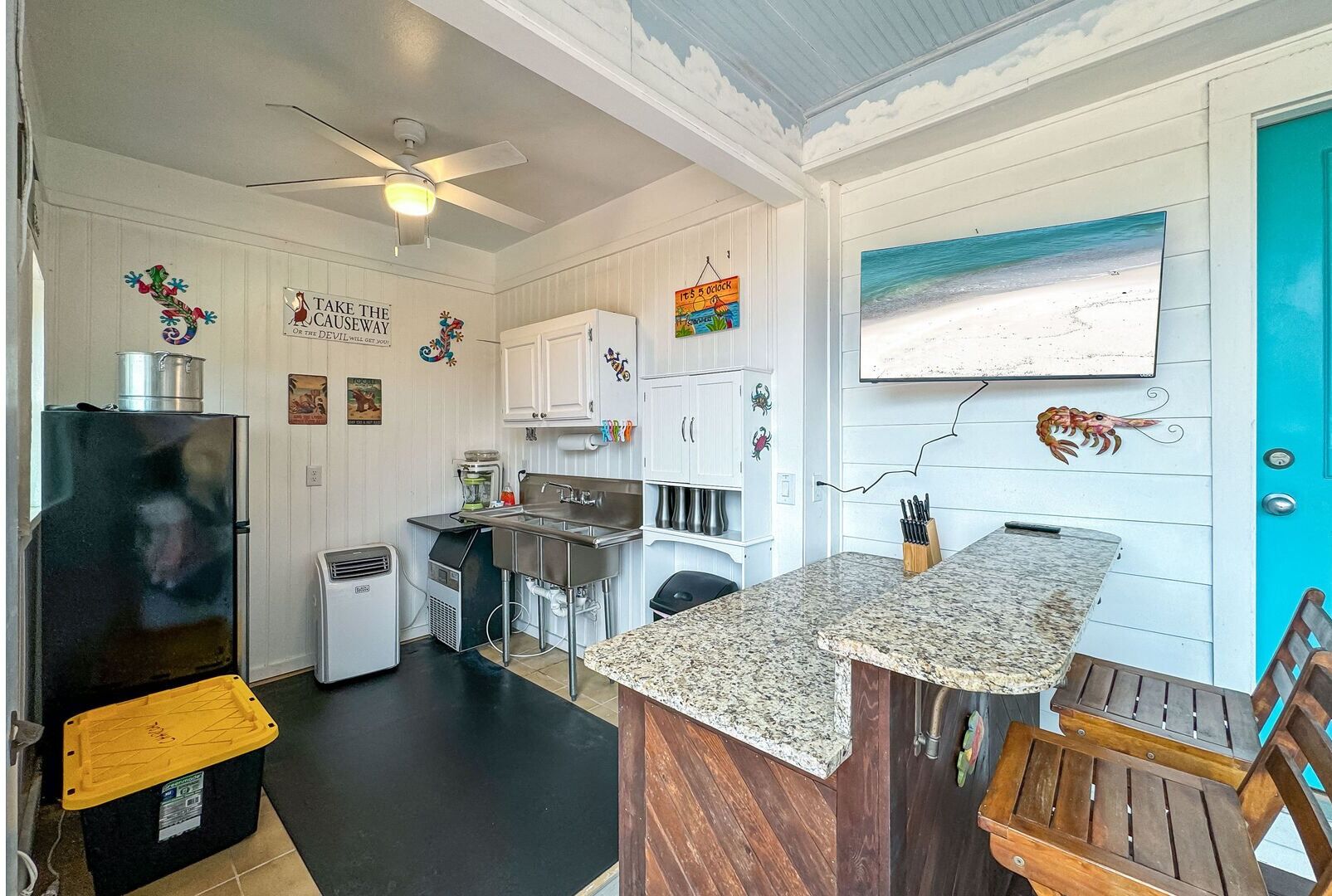 A compact kitchen with white cabinets, a granite countertop, and a small dining area with wooden chairs.