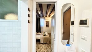 Une chambre d’hôtel avec un lit, une petite table avec un plateau, un miroir et une porte.