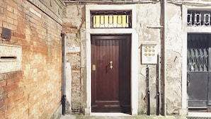 Una porta in legno con un cancello in metallo, un muro di mattoni e un cartello sopra la porta.