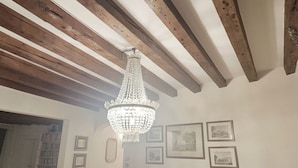 Una stanza caratterizzata da travi a vista in legno, un lampadario di cristallo e opere d'arte incorniciate alle pareti.