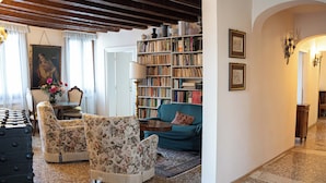 Un accogliente soggiorno con libreria, poltrone floreali, un divano verde e un tavolo da pranzo con sedie.