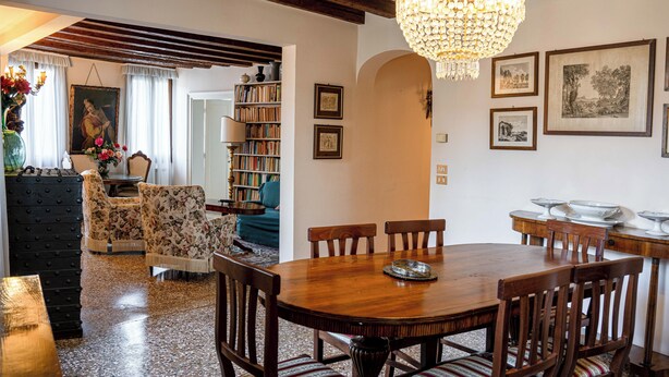 Un'area pranzo con un tavolo e sedie in legno, un lampadario e una libreria piena di libri.