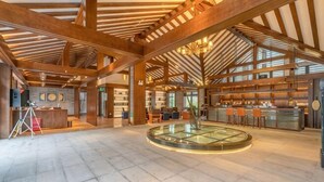 A spacious lobby with a central glass table, wooden beams, and a bar area. - Gongga cliff Hot Spring Hotel (Luding)