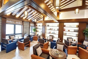 A spacious lobby with multiple seating areas, a central coffee table, and a large bookshelf. - Gongga cliff Hot Spring Hotel (Luding)