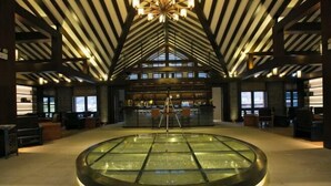 A spacious lobby with a central glass water feature, high ceilings with exposed beams, and a bar area in the background. - Gongga cliff Hot Spring Hotel (Luding)