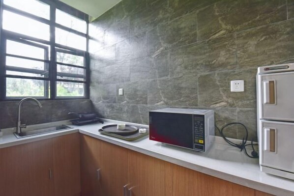 A kitchen with a stone backsplash, a microwave, a toaster, and a window with blinds. - Gongga cliff Hot Spring Hotel (Luding)