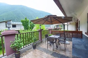A balcony with a table and chairs, a potted plant, and a view of a mountain. - Gongga cliff Hot Spring Hotel (Luding)