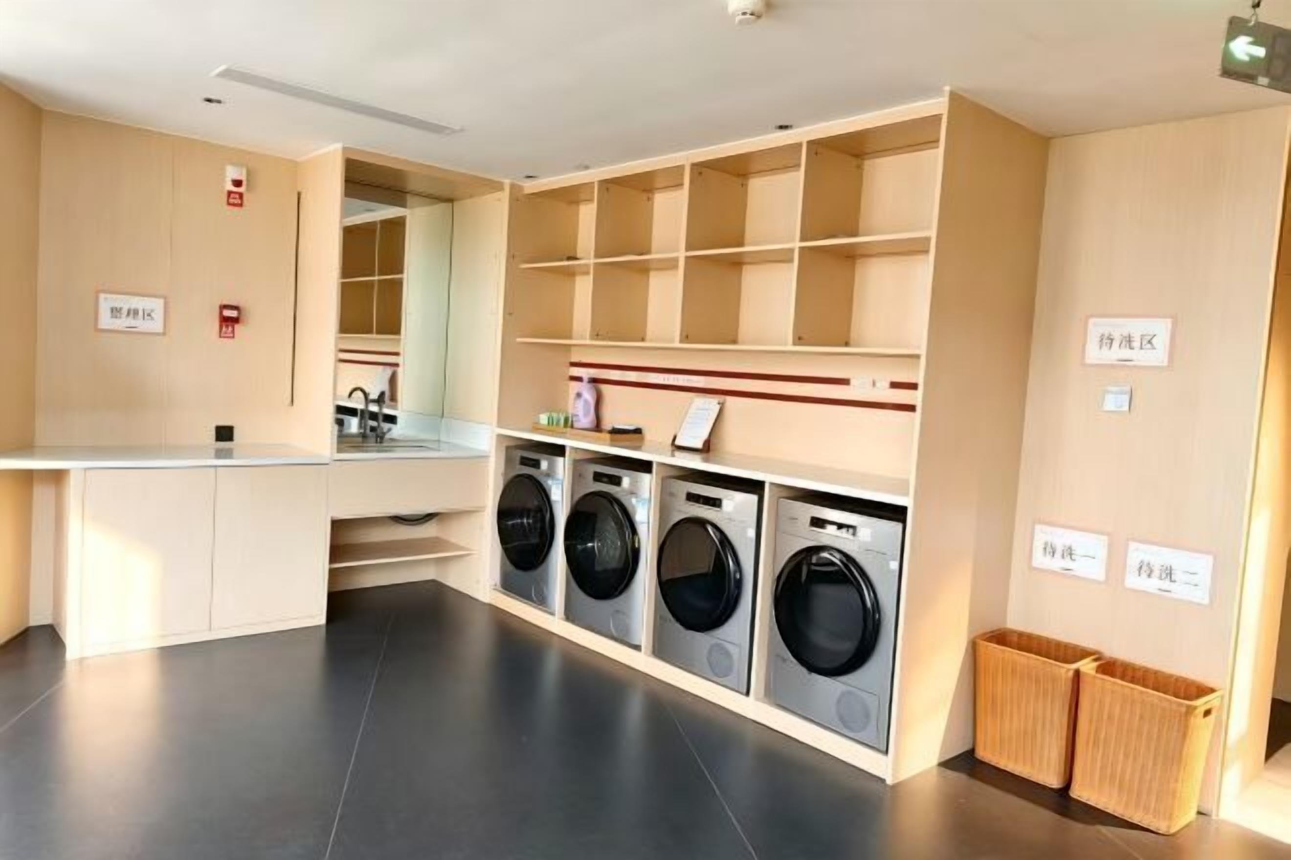 A laundry area with a washing machine, dryer, and shelves.
