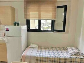 Cozy retreat with a bed, kitchenette, and natural light.