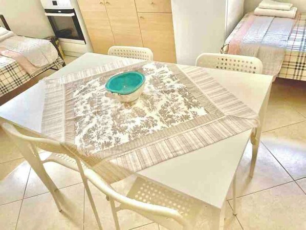Cozy room with a round table and single chair, featuring a light-colored floor and a small cabinet.
