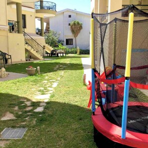 Enjoy a fun outdoor space with a trampoline, staircase, and pathway surrounded by lush greenery.