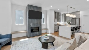 Una sala de estar moderna con chimenea, televisor de pantalla plana, una mesa redonda y un sofá.
