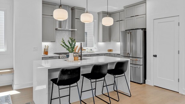 Una cocina moderna con una isla central, electrodomésticos de acero inoxidable e iluminación colgante.