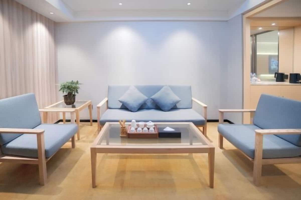 A modern hotel lobby with a sofa, two armchairs, a coffee table, and a small side table with a plant.