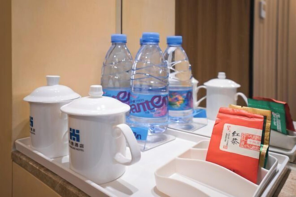 A hotel minibar with water bottles, a white mug, and tea packets.