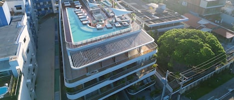 Un hôtel moderne doté d’une piscine sur le toit, de nombreux balcons et offrant une vue sur le paysage urbain environnant.