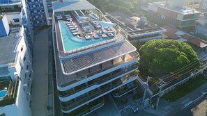 Un hôtel moderne doté d’une piscine sur le toit, de nombreux balcons et offrant une vue sur le paysage urbain environnant.