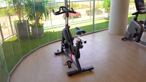 Una bicicleta estática en interiores con vista a un estacionamiento y áreas verdes.